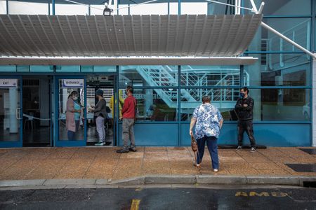 Voters jump over puddles while ducking the rain to get to the voting station
